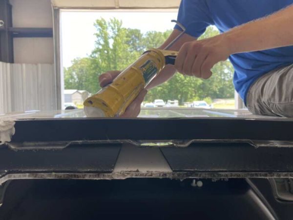 man caulks top of van
