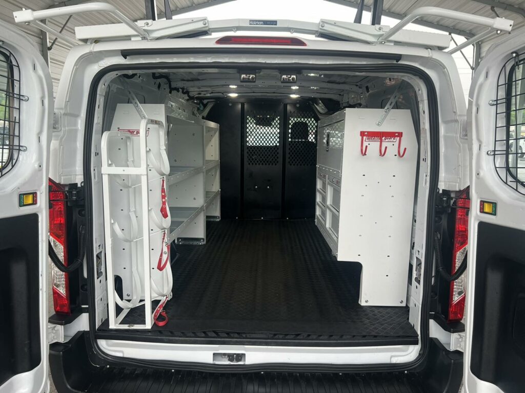 Work van with newly installed shelving unites, a partition, and new ladder rack with back doors opened to show ample storage space