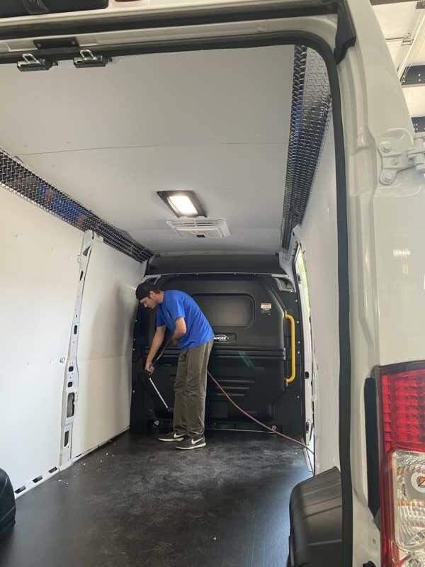 man in blue shirt cleans back of van