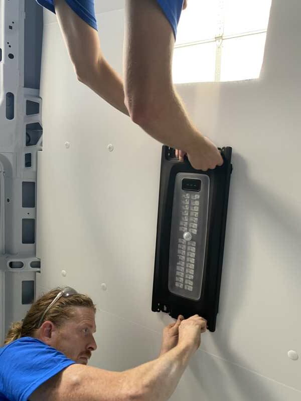 technician installs hardware on ceiling of van