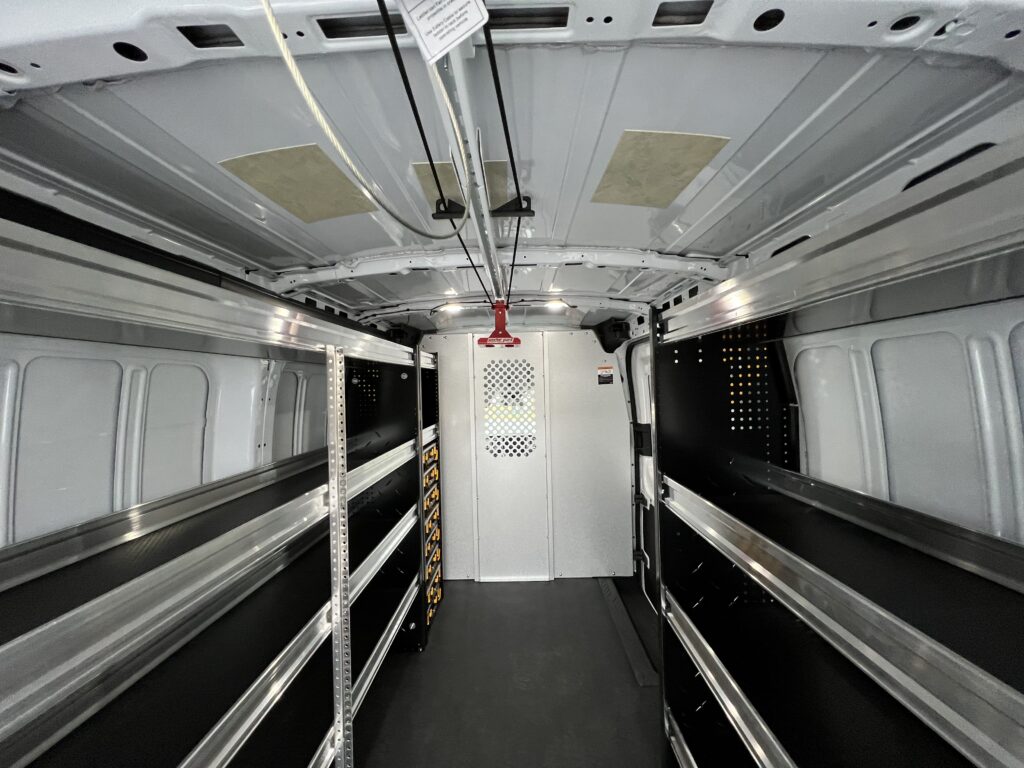 storage shelves, storage containers, and sliding ladder rack in interior of van